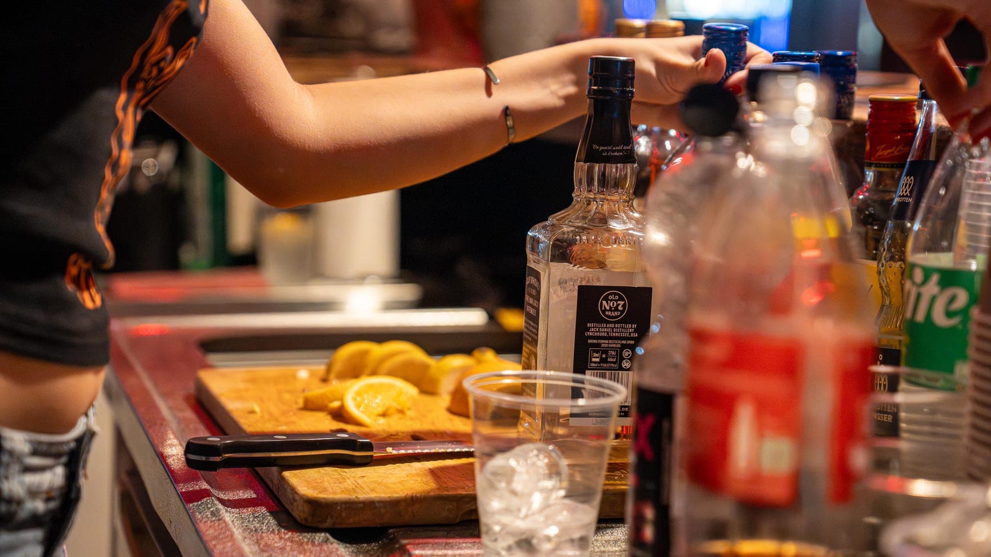 Tresen mit Whiskeyflasche, Orangen und Glas mit Eis