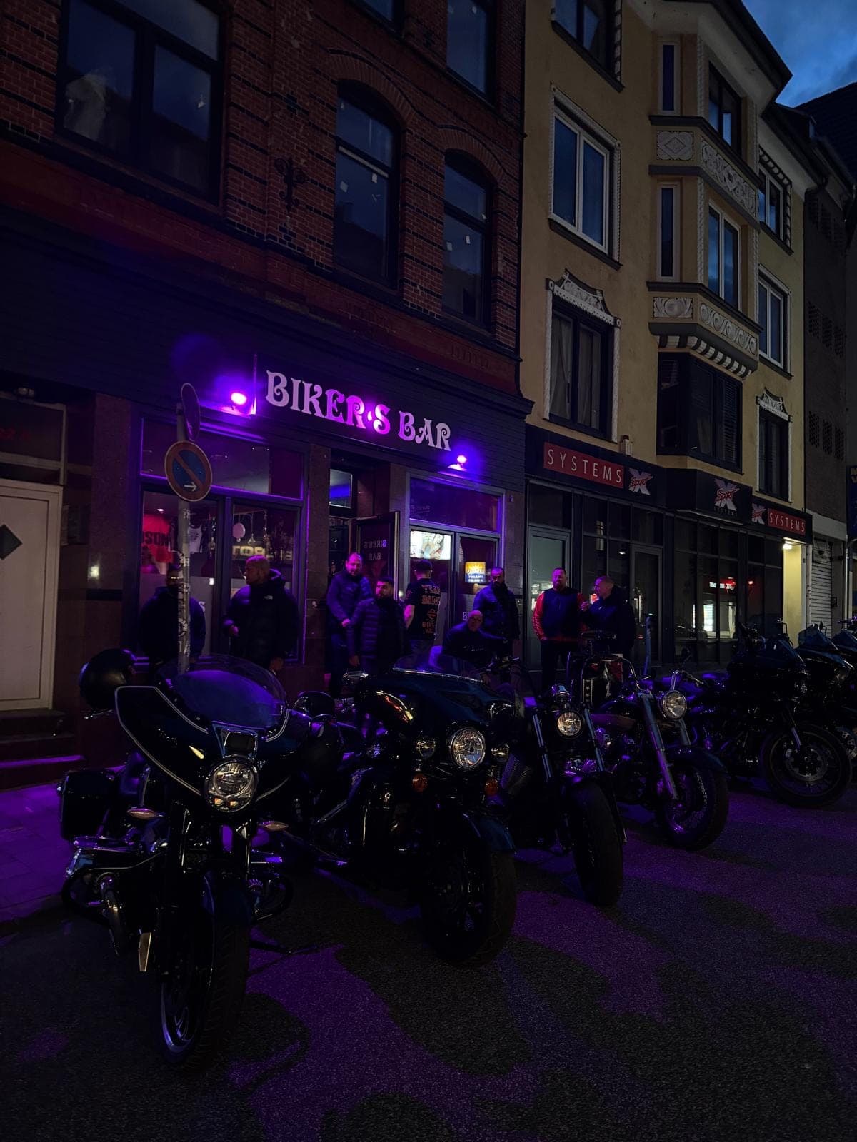 Fassade der Bar bei Nacht, Maschinen davor geparkt